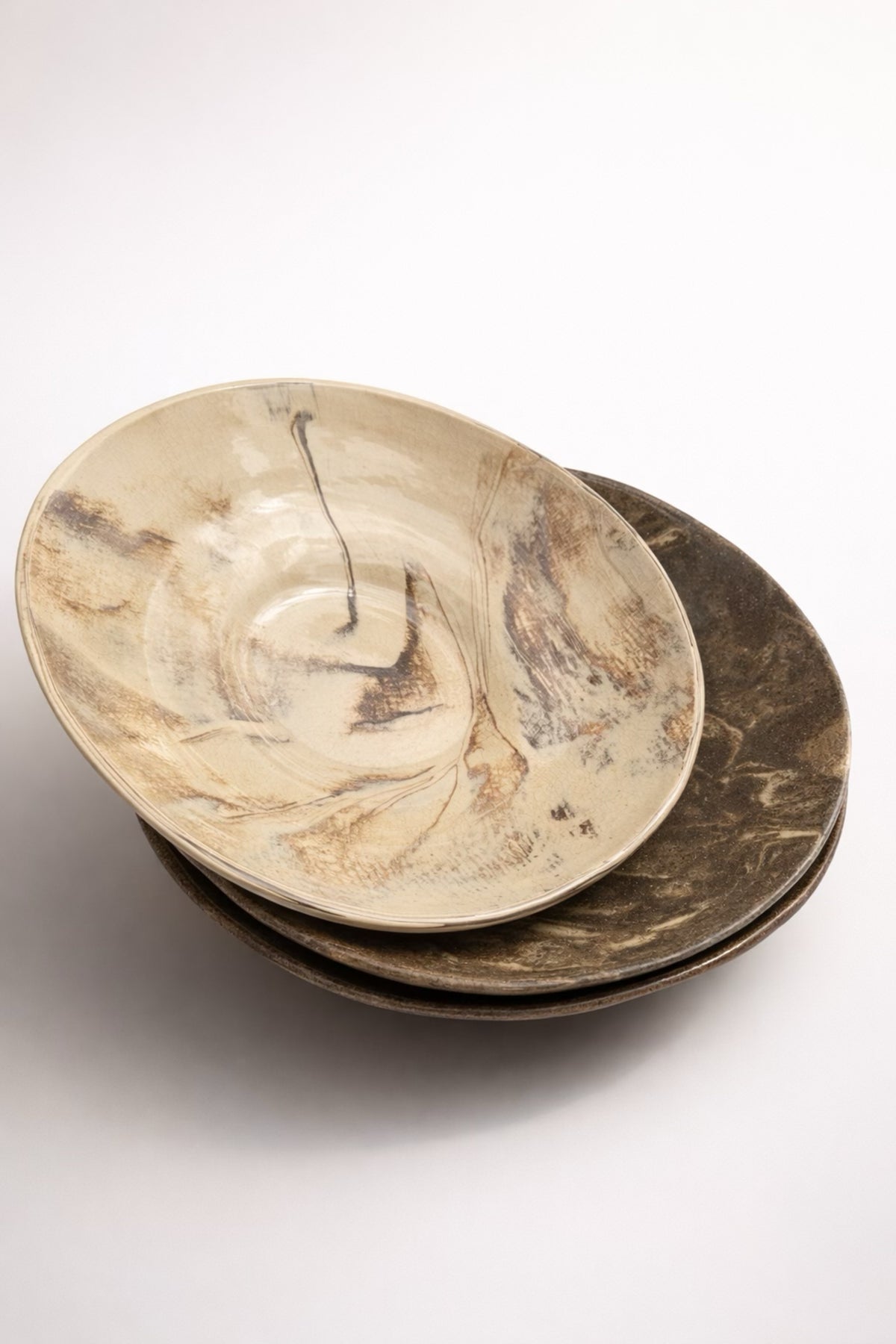 Handmade marbled ceramic plates stacked, cream and earth tones