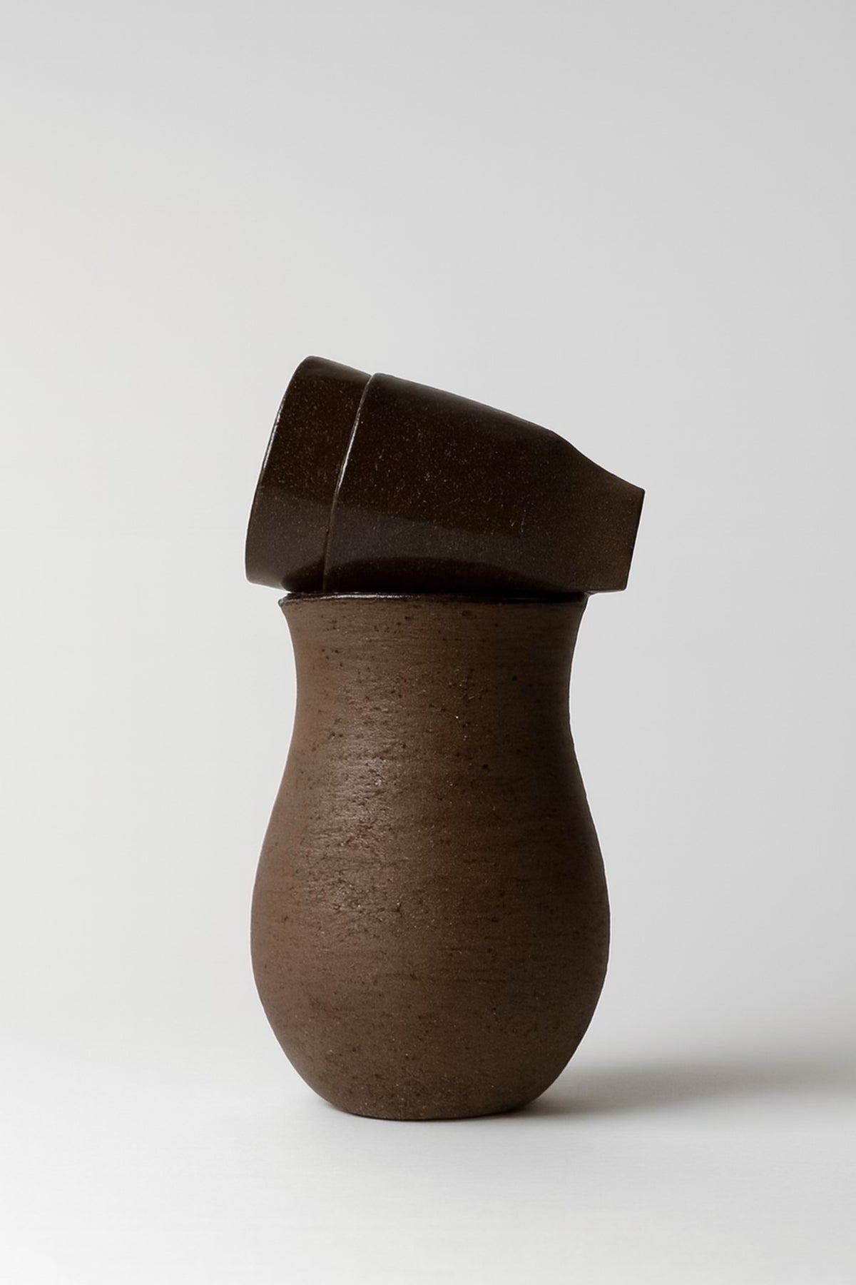 Tall dark brown matte stoneware vase with angled cylindrical lid