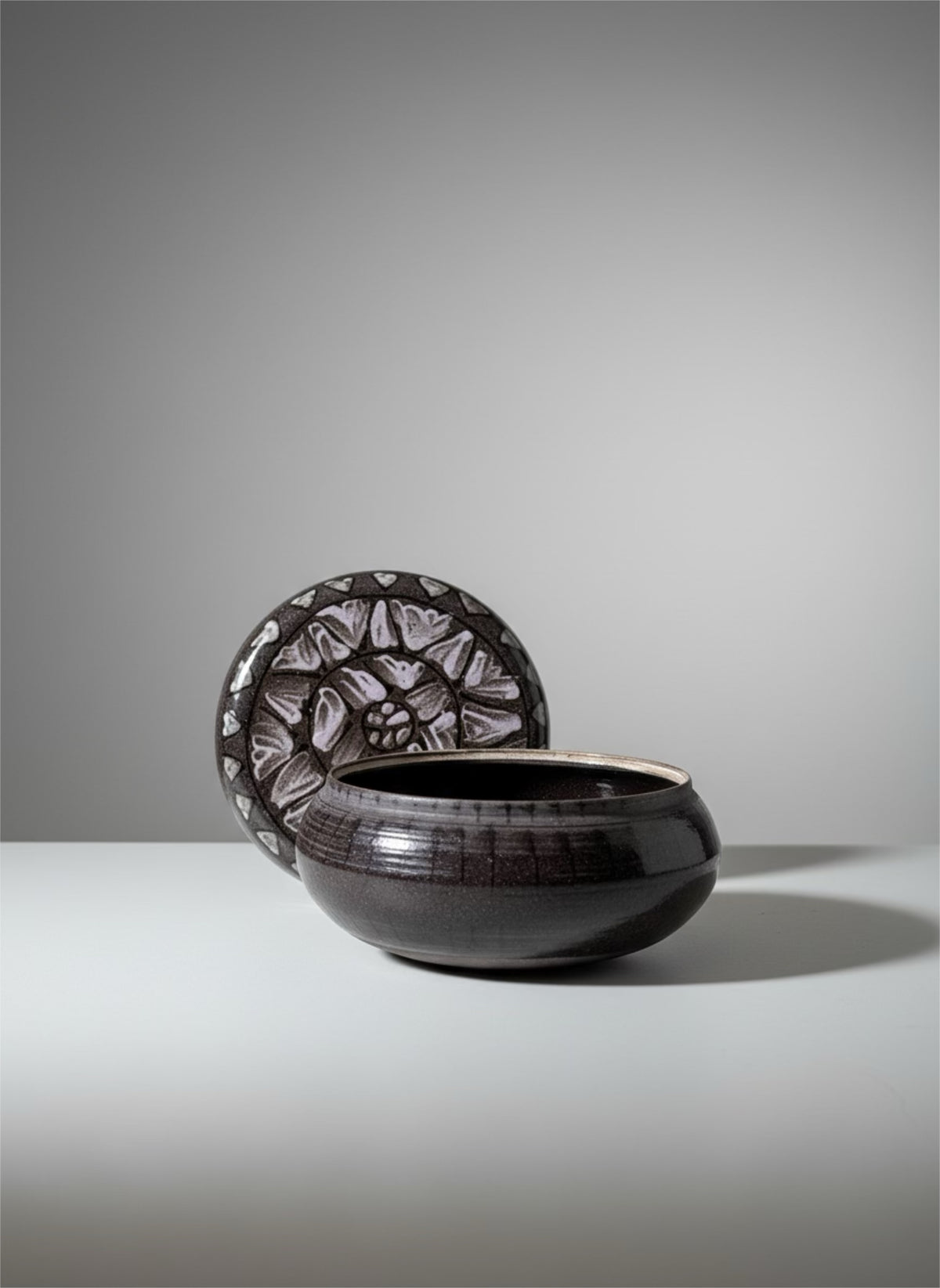 Black glazed ceramic bowl with hand-carved floral relief disc lid