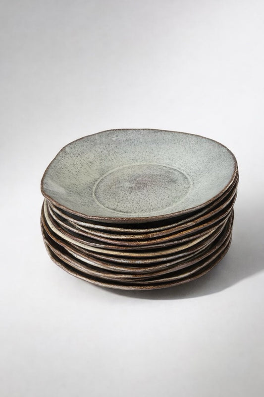 Stack of handmade ceramic Freedom Plates with organic edges and speckled grey-green glaze