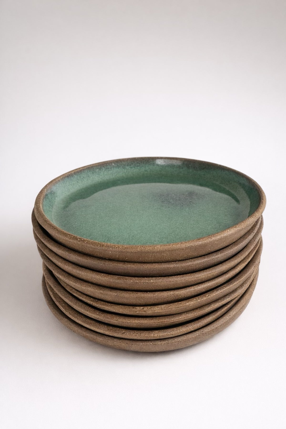 Stack of handmade ceramic plates with sage green glaze